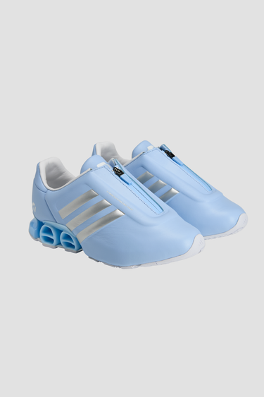 Light blue adidas athletic shoes with silver stripe white soles and a zipper tongue on a light gray background
