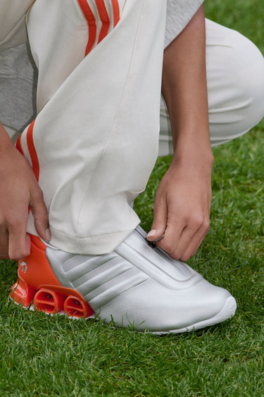 silver and orange adidas shoe with white sole and tongue zipper